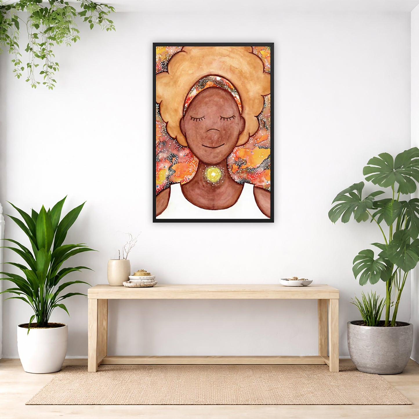 Framed poster of a woman mediating with a glowing throat chakra. The poster is in the center of the living room wall. Below the poster is a bench. On the bench is burning incense and a couple of bowls. There is a green potted plant on both the left and right side of the bench. There is a hanging plant on the left.
