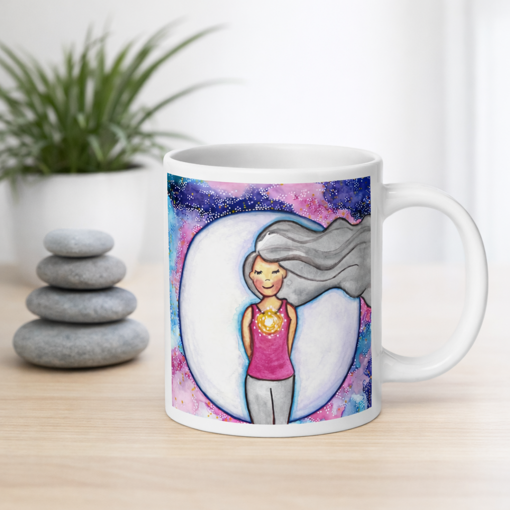 Meditating person with glowing heart chakra at center of chest, symbolizing love, compassion and emotional balance, spiritual design on a mindfulness coffee mug.  The mug is on a counter. Beside the mug are meditation stones. Behind the mug is a green potted plant.