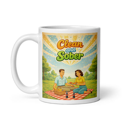 Mug with a design of two people having a picnic and the text 'Clean and Sober' on a white background. Sunburst sky.