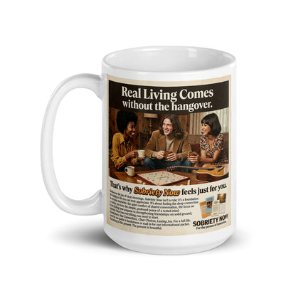 Mug with a graphic of people playing dominoes and text about sobriety, on a white background. Real living comes without the hangover.