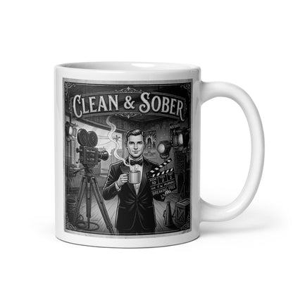 Black and white vintage illustration coffee mug featuring a tuxedo-clad man on a 1920s silent film set holding a steaming coffee mug and a clapperboard reading "Breaking Free" surrounded by period cameras and studio lights with "Clean & Sober" in marquee lettering
