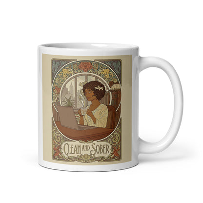 Beautiful and striking Art Nouveau style coffee mug featuring a Black woman with flowers in her hair sitting at a desk with a laptop and coffee cup, framed by ornate botanical scrollwork with "Clean and Sober" in vintage lettering
