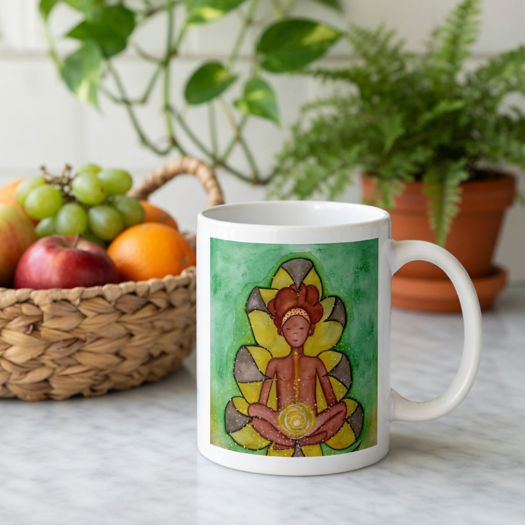 Meditating figure with glowing sacral chakra below the navel, representing creativity, passion and emotional flow, spiritual chakra artwork on a coffee mug.  Behind the mug is a basket of fruit and a green potted plant.
