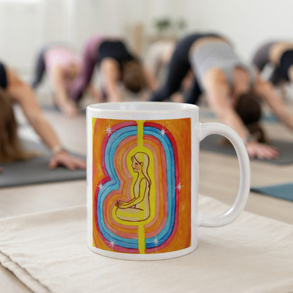 Woman surrounded by radiant multi-colored aura, representing energy, emotion and spiritual awareness, vibrant mindfulness artwork on a coffee mug.   The mug is in front of a yoga class doing the downward facing dog posture.