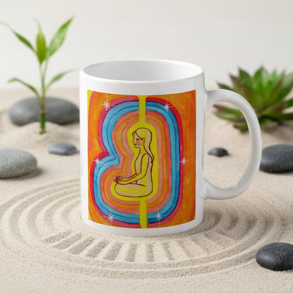 Woman surrounded by radiant multi-colored aura, representing energy, emotion and spiritual awareness, vibrant mindfulness artwork on a coffee mug.   The mug is in a beautifully raked zen garden with bushes and plants behind it.