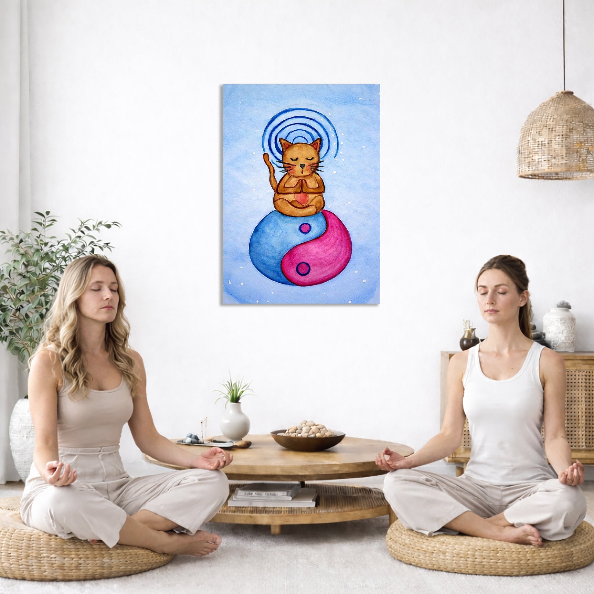 Brown cat meditating on a yin yang symbol with its crown chakra vibration. This is a print of the original hand-painted watercolor by Brazilian artist Thaís Suizo for the LET'S MEDITATE SERIES of mediation guides.  The poster is in the center of the living room wall. Two women are sitting on a giant pillow having a coffee. Beside them is a small tray with a pot of coffee and incense. To the left is a green floor plant and a hanging green plant. To the right of them is a green floor plant.