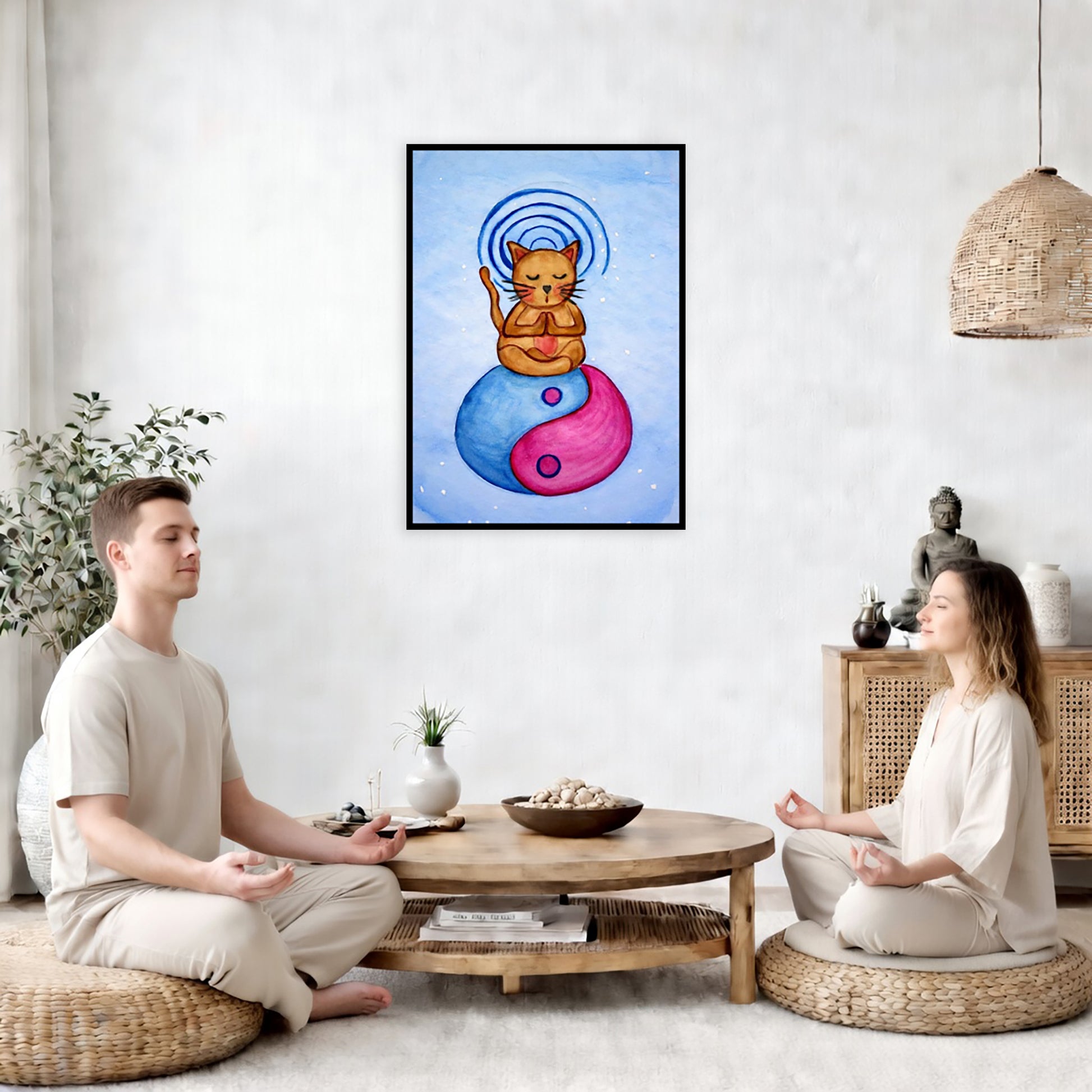 Brown cat meditating on a yin yang symbol with its crown chakra glowing framed poster.  This is a print of the original hand-painted watercolor by Brazilian artist Thaís Suizo. The poster is in the center of the living room wall. Two friends are sitting on wicker pillows meditating. Between them is a small round coffee table with incense, a green potted plant and a bowl of shells. There is a potted plant to the left and a Buddha statue and a vase to the right. 