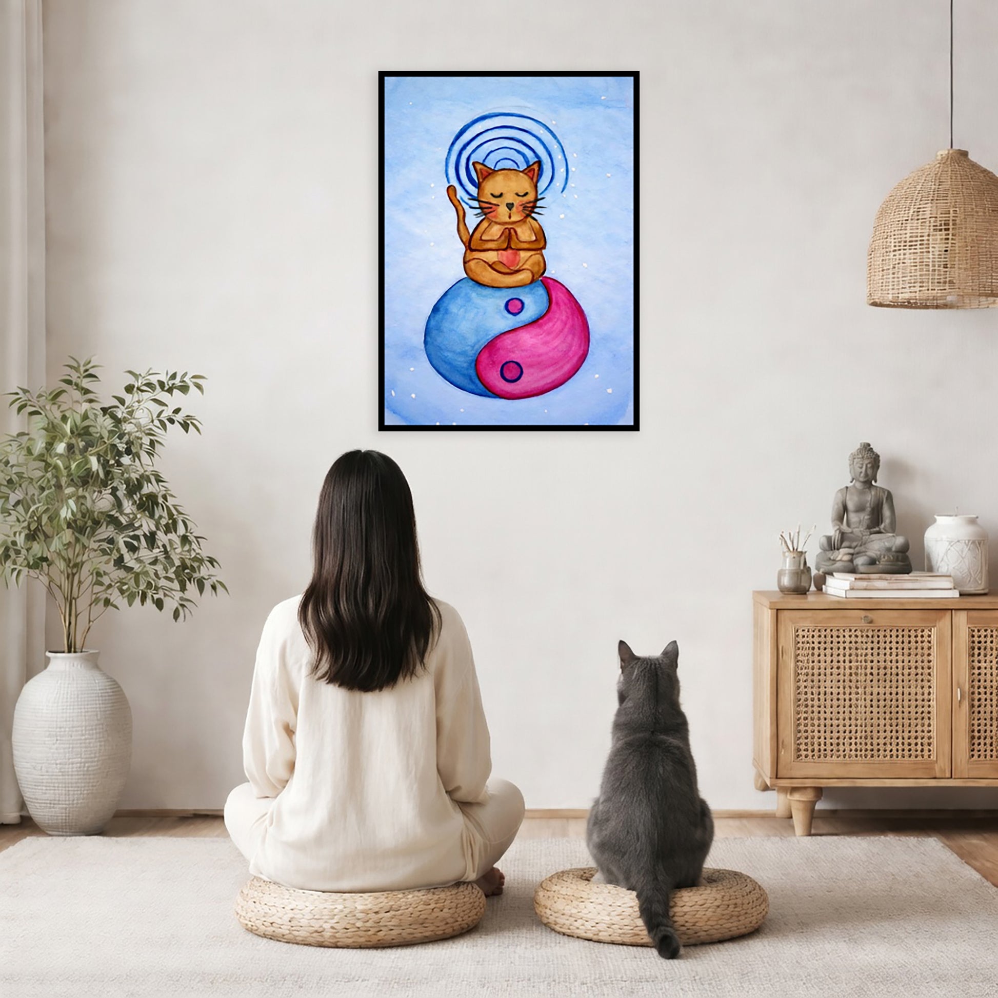 Brown cat meditating on a yin yang symbol with its crown chakra glowing framed poster.  This is a print of the original hand-painted watercolor by Brazilian artist Thaís Suizo.  The poster is in the center of the living room wall. A woman and a cat are staring up at the poster. There is a potted plant on the left side and a cabinet with a Buddha statue, books and incense on the right side.