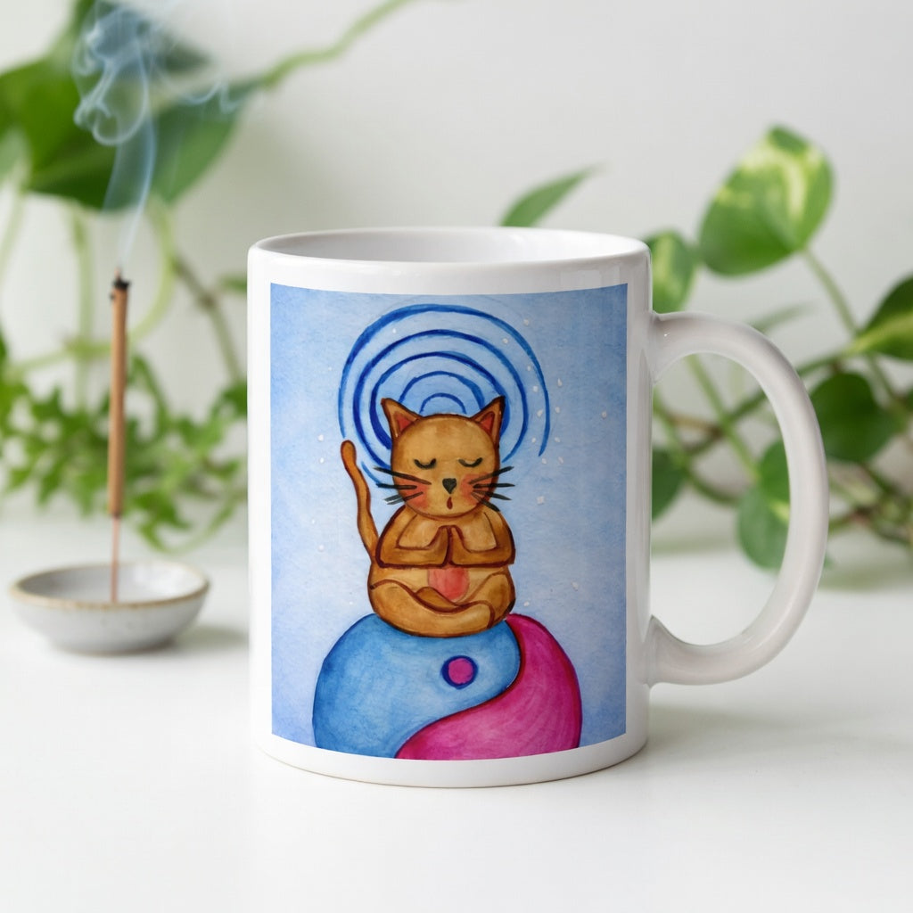 Brown cat meditating on top of a blue and magenta Tao symbol with a glowing crown chakra above its head meditation mug.  Incense is burning behind the mug. There is a green potted plant in the background.