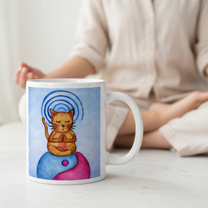 Brown cat meditating on top of a blue and magenta Tao symbol with a glowing crown chakra above its head meditation mug.  A woman is meditating in the background.