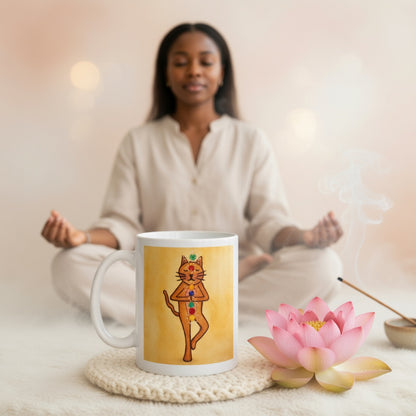 Brown cat standing in a meditation pose with glowing chakras along its body on a yellow background meditation mug.  The mug is sitting on a white mat beside a  pink lotus flower and burning incense beside it. A woman is meditating in the background.