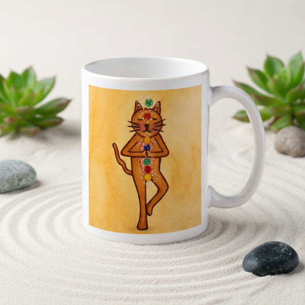 Brown cat standing in a meditation pose with glowing chakras along its body on a yellow background meditation mug.  The mug is in a beautifully raked zen garden with bushes and plants behind it.