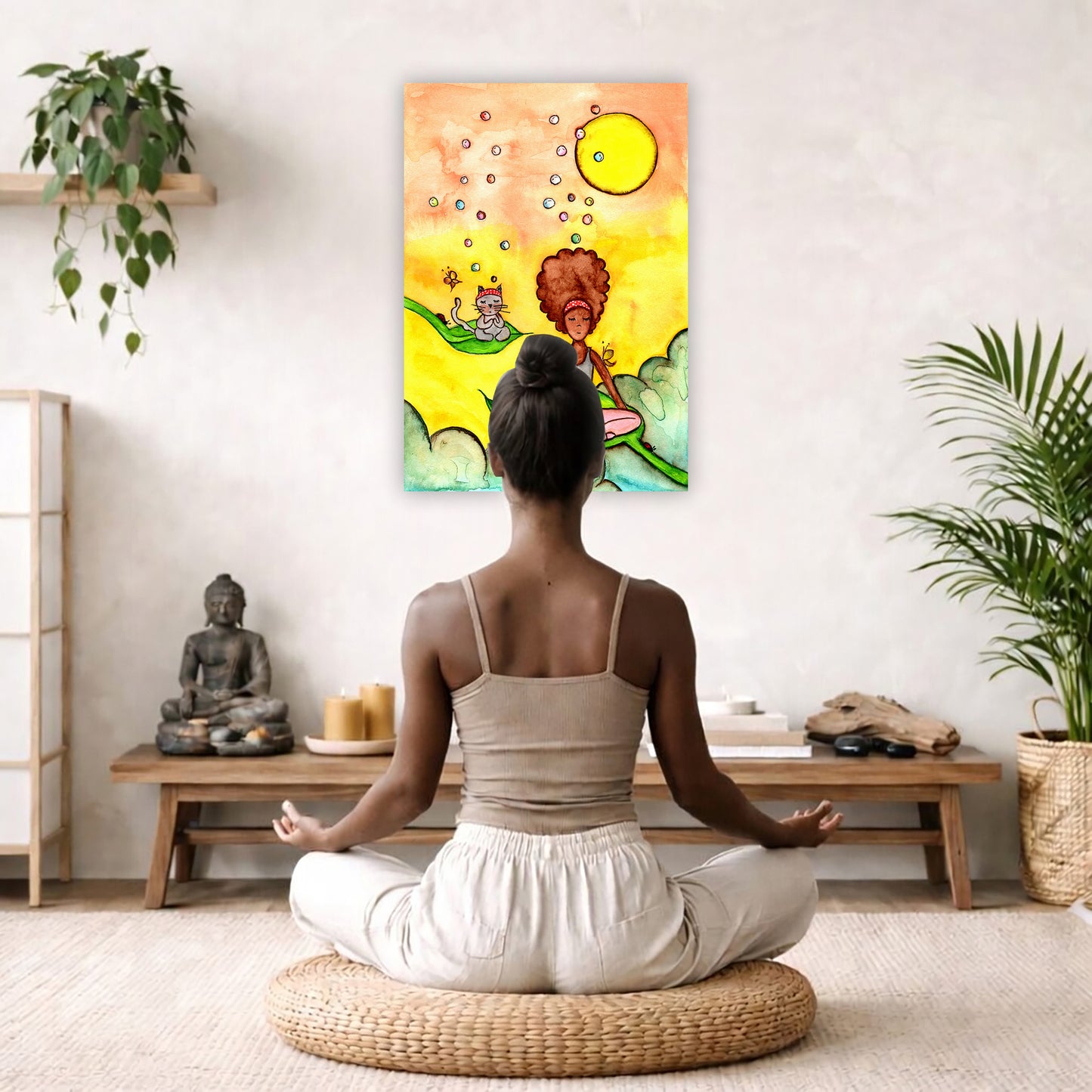 Canvas of a woman and her cat meditating while sitting on leaves. The background is bright yellow.  The canvas is hanging on a living room wall. A woman is mediating facing the poster. There is a coffee table in front of her with burning candles and a Buddha statue. There are green potted plants on each side of the room.
