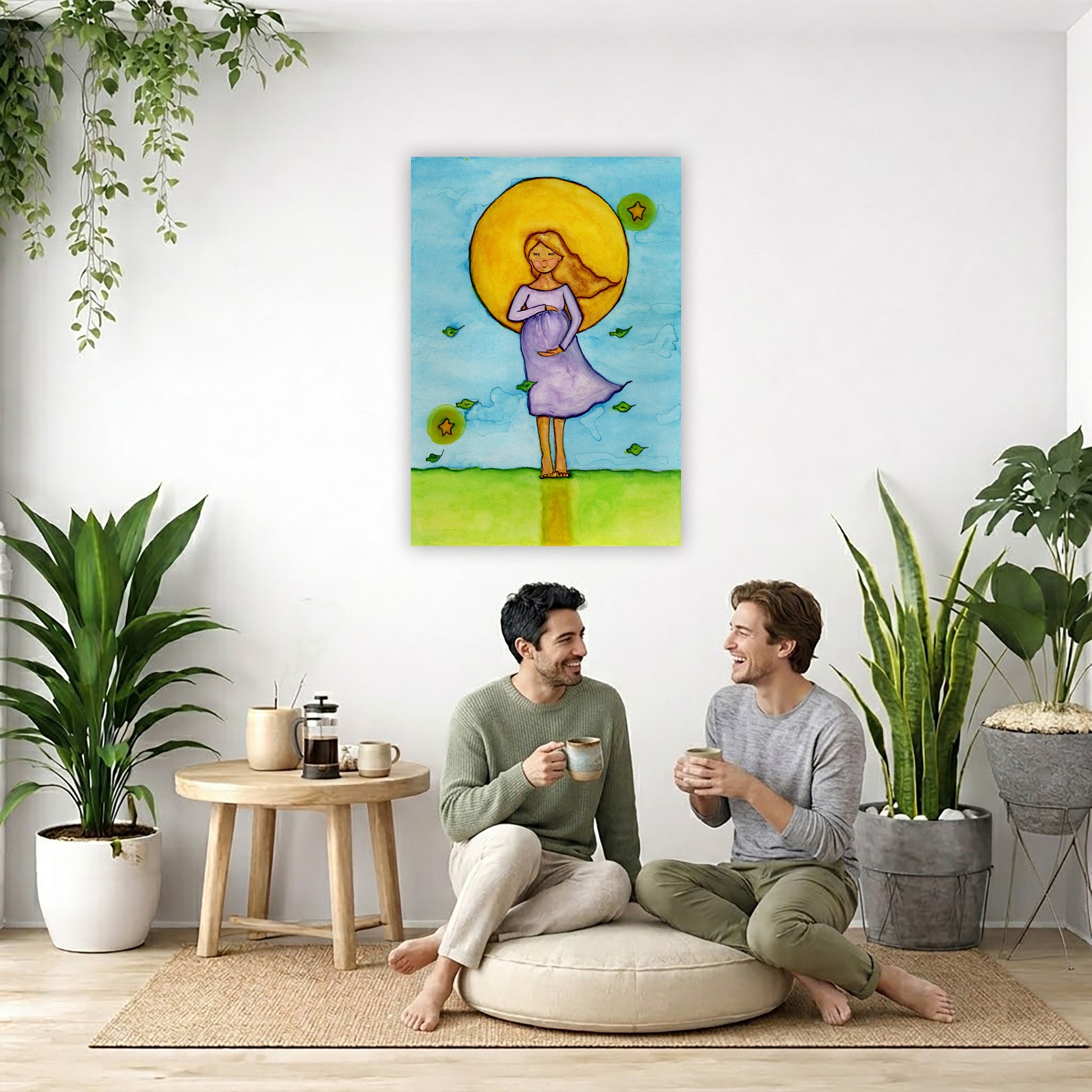 A woman standing in meditation under a bright yellow sun with a blue sky background, canvas watercolor print. The canvas is in the center of the living room wall. Two men are sitting on a giant pillow having a coffee. Beside them is a small tray with a pot of coffee and incense. To the left is a green floor plant and a hanging green plant. To the right of them is a green floor plant.