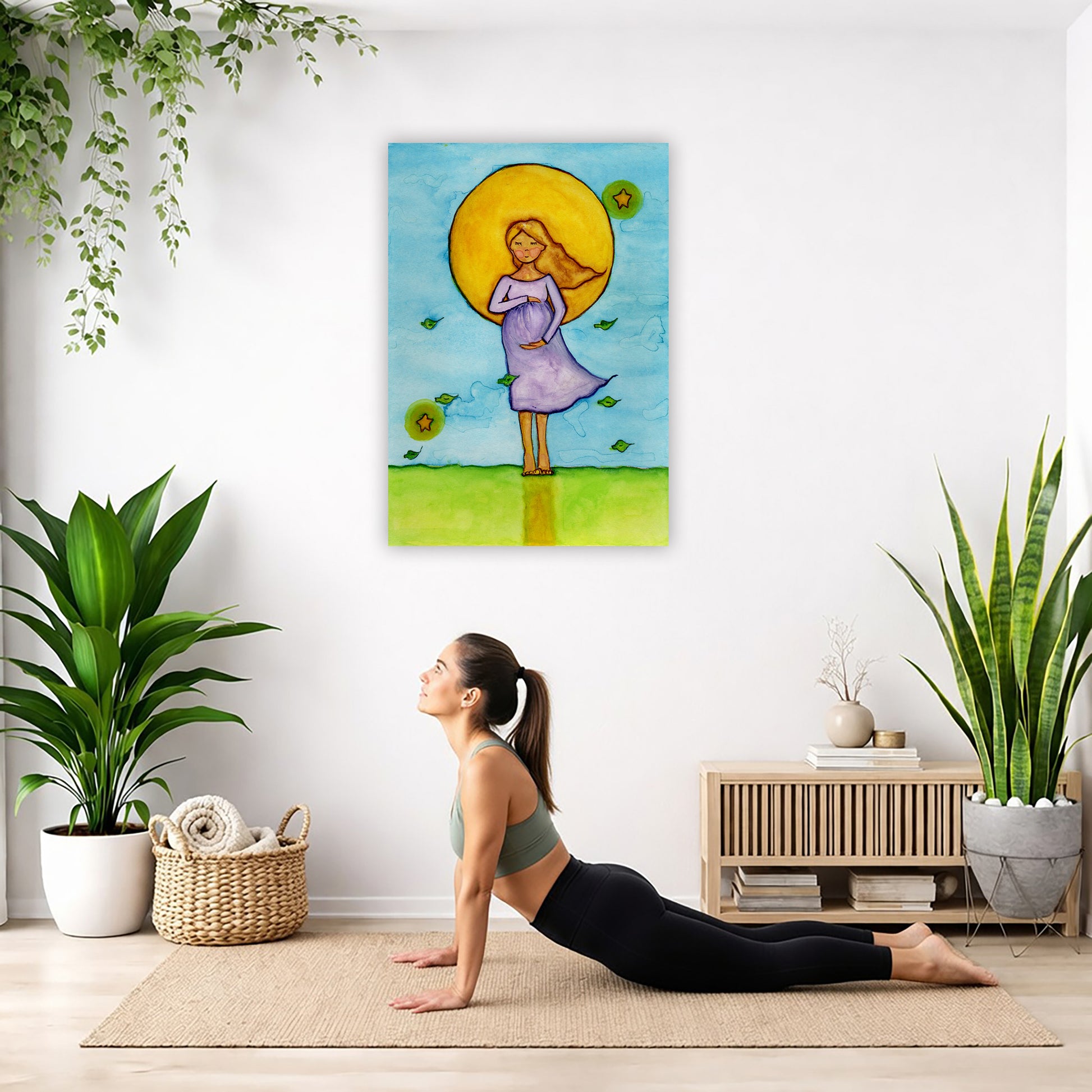 A woman standing in meditation under a bright yellow sun with a blue sky background, canvas watercolor print.  The canvas is in the center of the living room wall. Below the poster a woman is doing the yoga posture downward facing dog on a yoga mat.