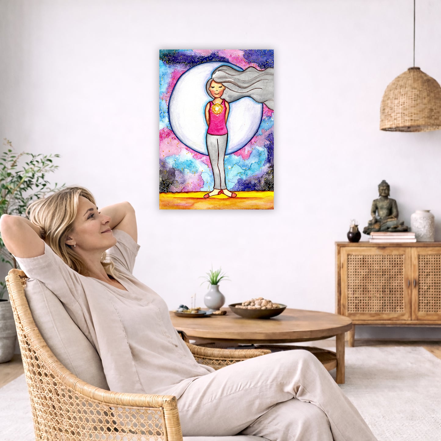 Poster of a woman's heart chakra glowing with love energy.  The poster is in the center of the living room wall. To the left a woman is relaxing in her chair with her hands behind her head. There is a small coffee table beside her with a bowl of walnuts, incense and a small green plant. On the right side of the room is a cabinet with a Buddha statue, books and an urn on it. To the left is a green floor plant.

