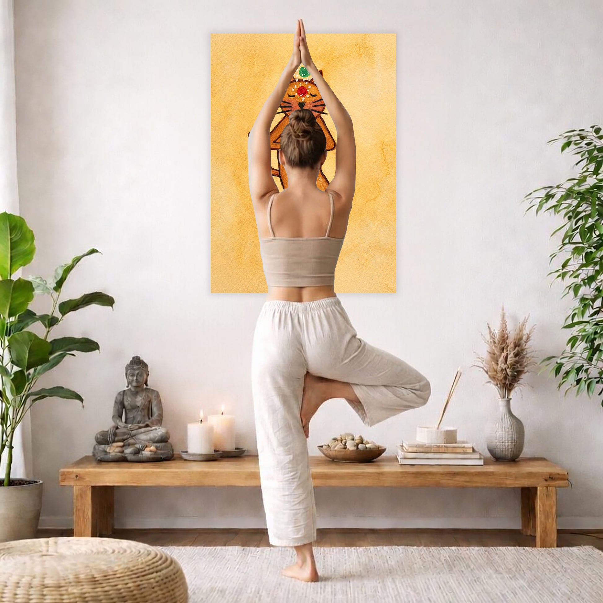 A poster with a brown cat in standing meditation pose with glowing chakras aligned along the body. The poster is framed hanging on a living room wall. A woman is doing the yoga tree pose (Vrksasana) facing the poster. There is a coffee table in front of her with candles and a Buddha statue. There are green potted plants on each side of the room.
