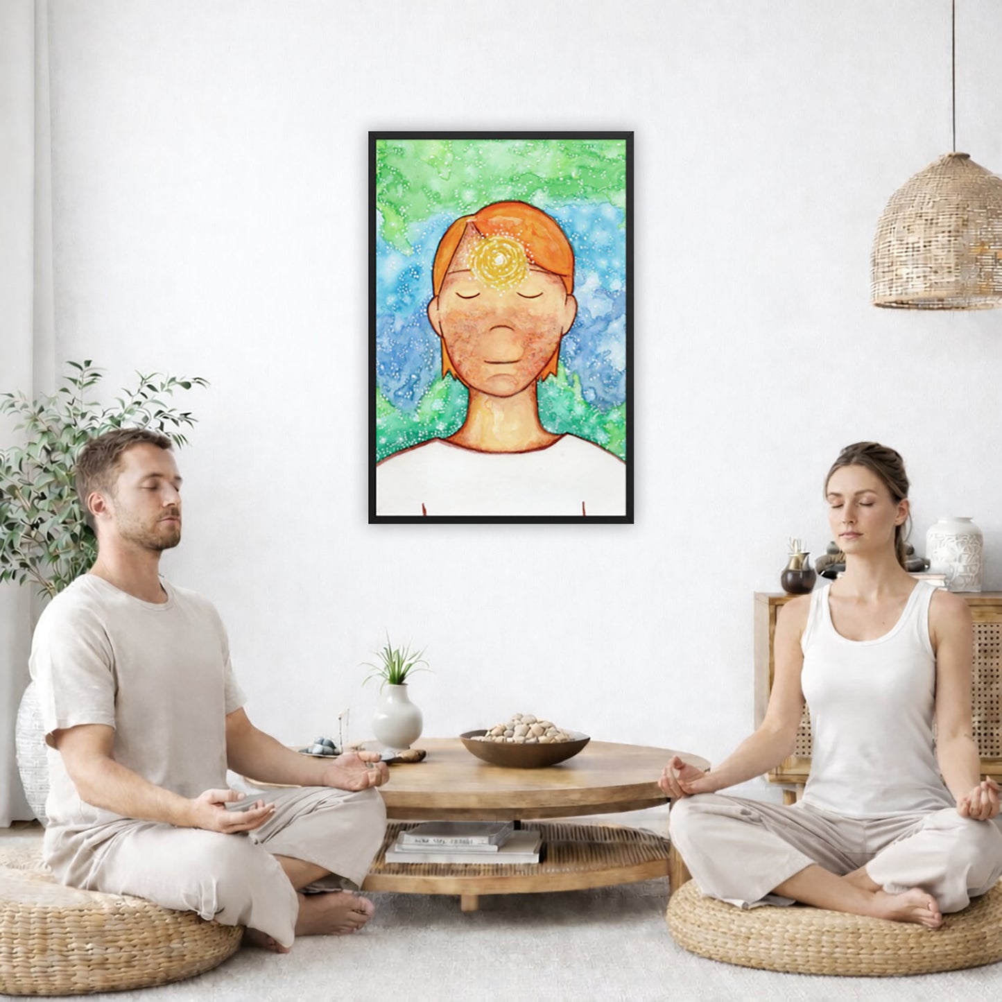 Framed poster of a man with a glowing brow chakra. The poster is in the center of the living room wall. Two friends are sitting on wicker pillows meditating. Between them is a small round coffee table with incense, a green potted plant and a bowl of shells. There is a potted plant to the left and a Buddha statue and a vase to the right. 
