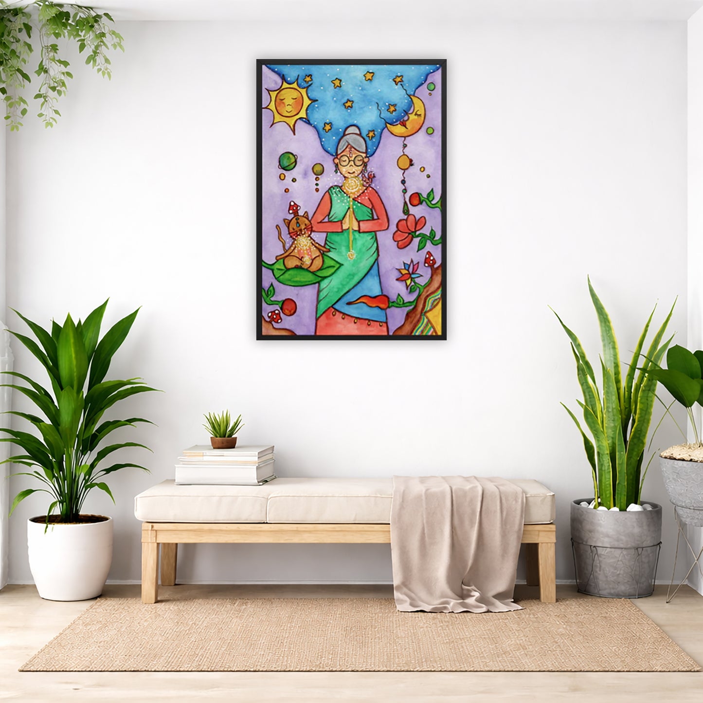 Framed poster of woman in standing prayer meditation with glowing throat chakra under sun and moon. Her cat is meditating beside her.  The poster is in the center of the living room wall. Below the poster is a padded bench. On the bench is a pile of books and a small green potted plant. There is a silk sheet draped over the bench. There is a green hanging plant and floor plant on the left. There are two floor plants on the right.