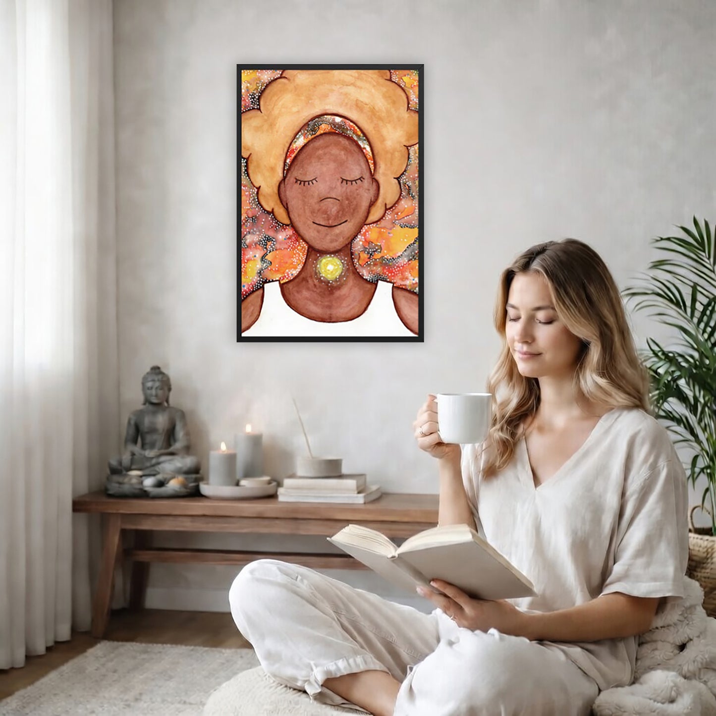 Framed poster of a woman mediating with a glowing throat chakra. The poster is on the back wall in the living room. There is a coffee table below the poster with burning candles and a big piece of driftwood. A woman is sitting in a wicker chair on the right side of the poster with a cup of tea reading a book. There is a potted green plant behind her.