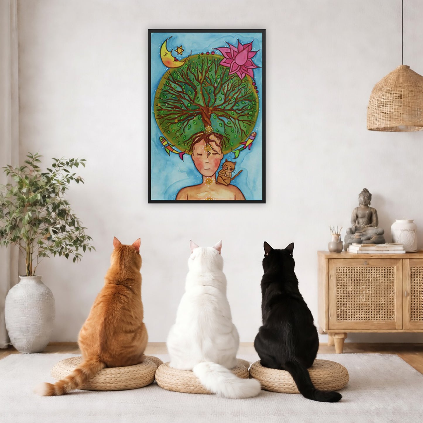 Framed poster of the crown chakra of a woman opening up like the tree of life. A cat is on her shoulder. The poster framed is hanging on the wall. Three cats are staring up at the poster, orange, white and black. There is a potted plant on the left side and a cabinet with a Buddha statue, books and incense on the right side.
