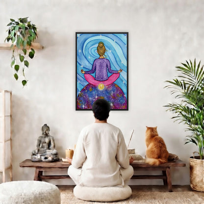 Framed poster of a woman meditating on top of the world with her root chakra glowing. The poster is in the center of the living room wall. A man is meditating facing the poster. In front of him is a coffee table with a Buddha statue and burning candle on the left and incense and an orange cat staring at the poster on the right. There is a green potted plant on both the left and right side of the coffee table.