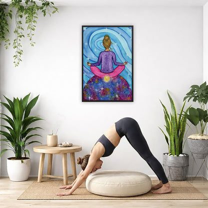 Framed poster of a woman meditating on top of the world with her root chakra glowing. The poster is in the center of the living room wall. Below the poster a woman is doing the yoga posture downward facing dog on a yoga mat.