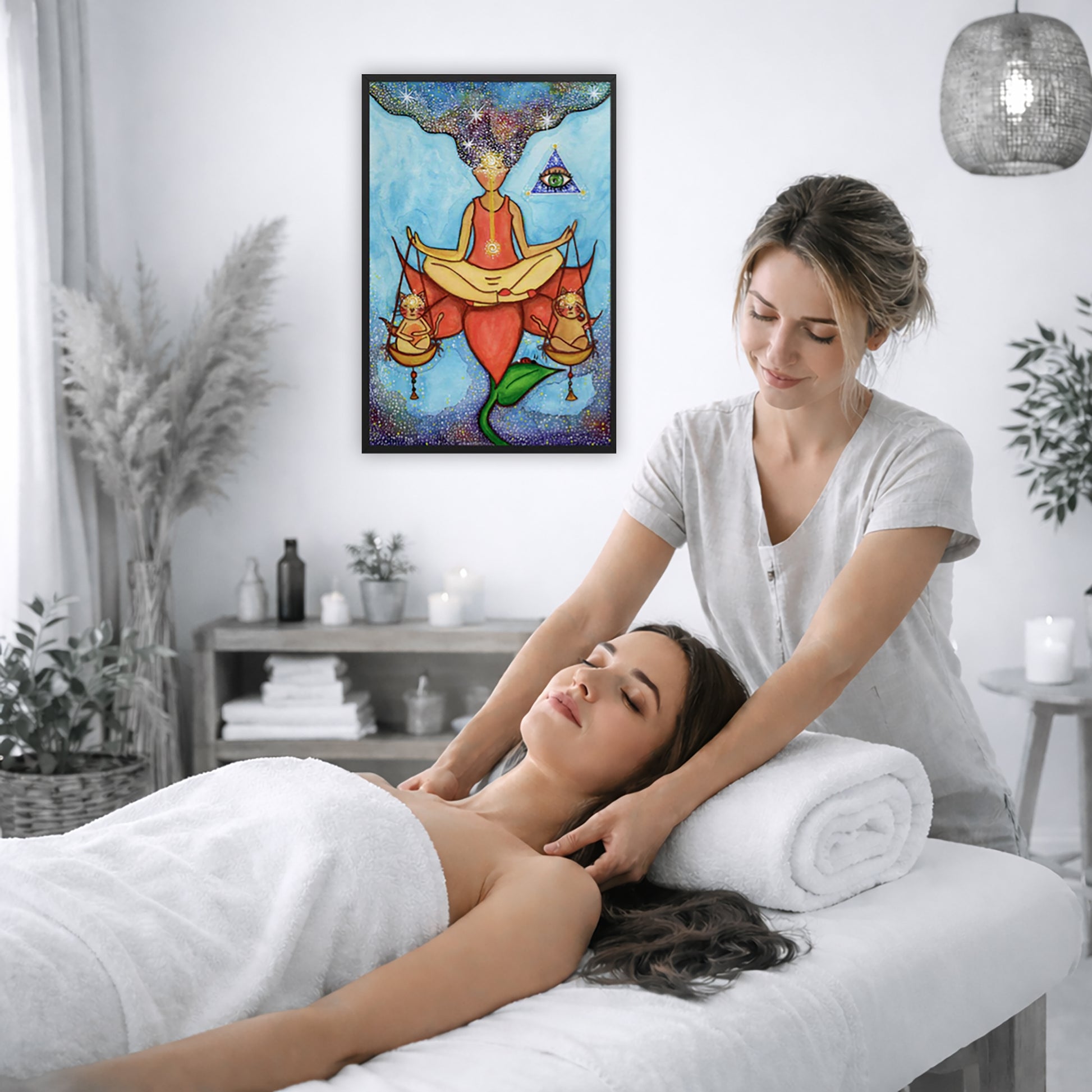 Framed poster of a woman sitting on a lotus with a glowing brow chakra holding a large set of scales.  The poster is on the wall of the office of a massage therapist. The therapist is giving her female client a massage. The client is lying face up on a massage table wearing a white towel. To the left is a window, floor plant and large vase of dry flora. A shelf is underneath the poster with candles burning. There is a candle burning on a small table and a hanging lamp with a wicker shade on the right side.
