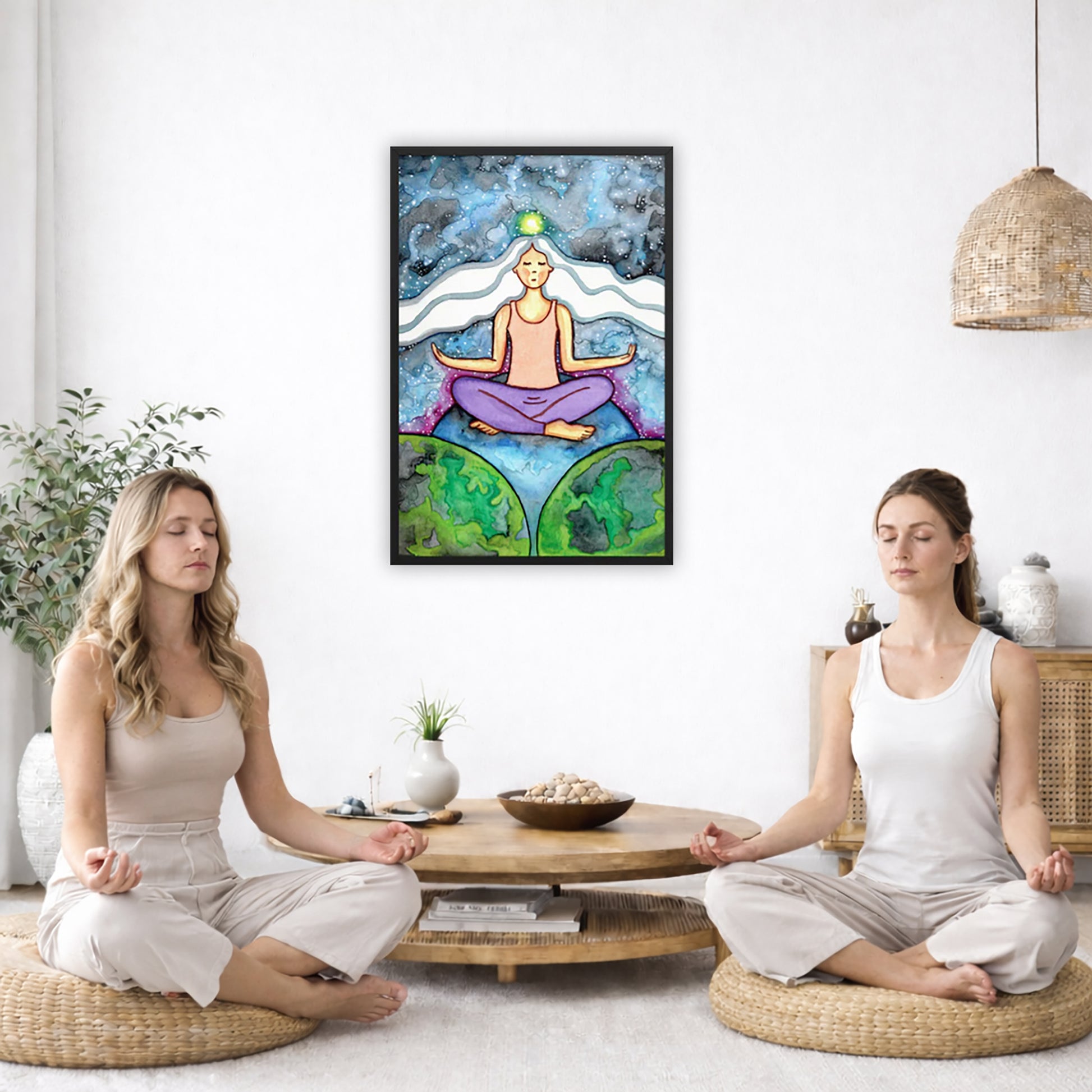 Framed poster of a meditating woman with her crown chakra glowing. The poster is in the center of the living room wall. Two women are sitting on a giant pillow having a coffee. Beside them is a small tray with a pot of coffee and incense. To the left is a green floor plant and a hanging green plant. To the right of them is a green floor plant.