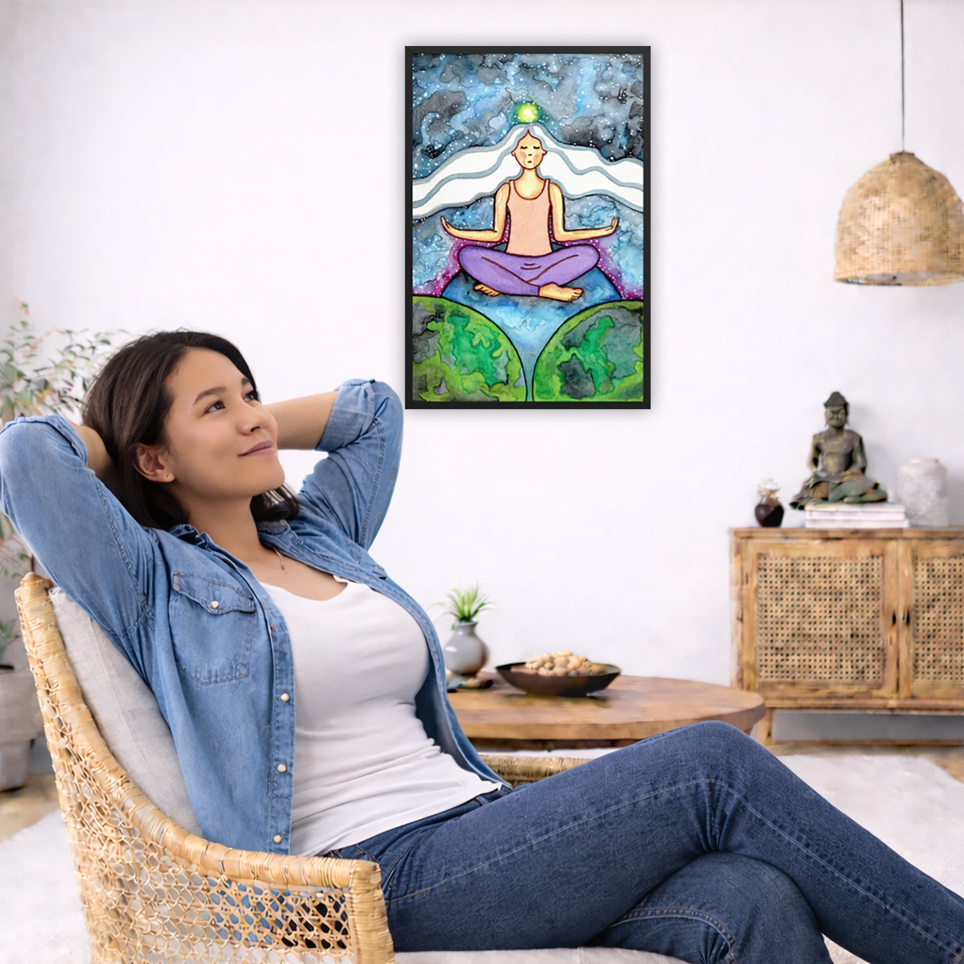 Framed poster of a meditating woman with her crown chakra glowing.  The poster is in the center of the living room wall. To the left a woman is relaxing in her chair with her hands behind her head. There is a small coffee table beside her with a bowl of walnuts, incense and a small green plant. On the right side of the room is a cabinet with a Buddha statue, books and an urn on it. To the left is a green floor plant.