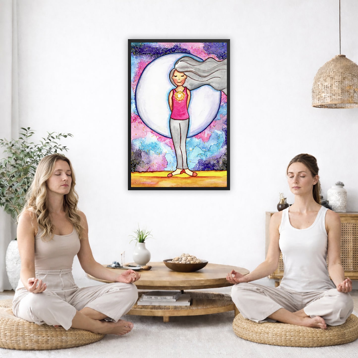 Framed poster of a woman's heart chakra glowing with beautiful love energy.  The poster is in the center of the living room wall. Two women are sitting on a giant pillow having a coffee. Beside them is a small tray with a pot of coffee and incense. To the left is a green floor plant and a hanging green plant. To the right of them is a green floor plant.