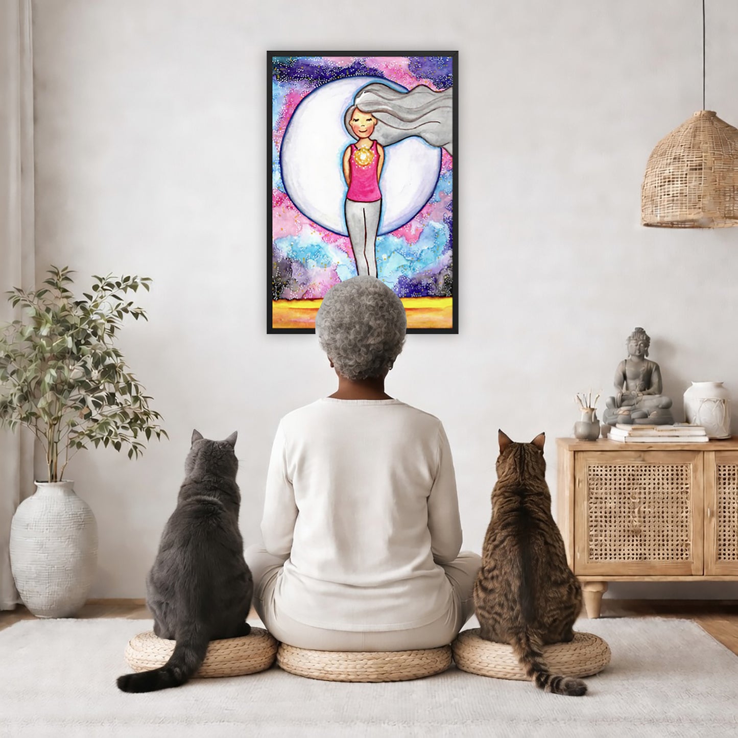 Framed poster of a woman's heart chakra glowing with beautiful love energy. The poster is in the center of the living room wall. A woman is meditating facing the poster with a white cat on her left side and a black cat on her right side. There is a potted plant on the left side and a cabinet with a Buddha statue on it on the right side. 
