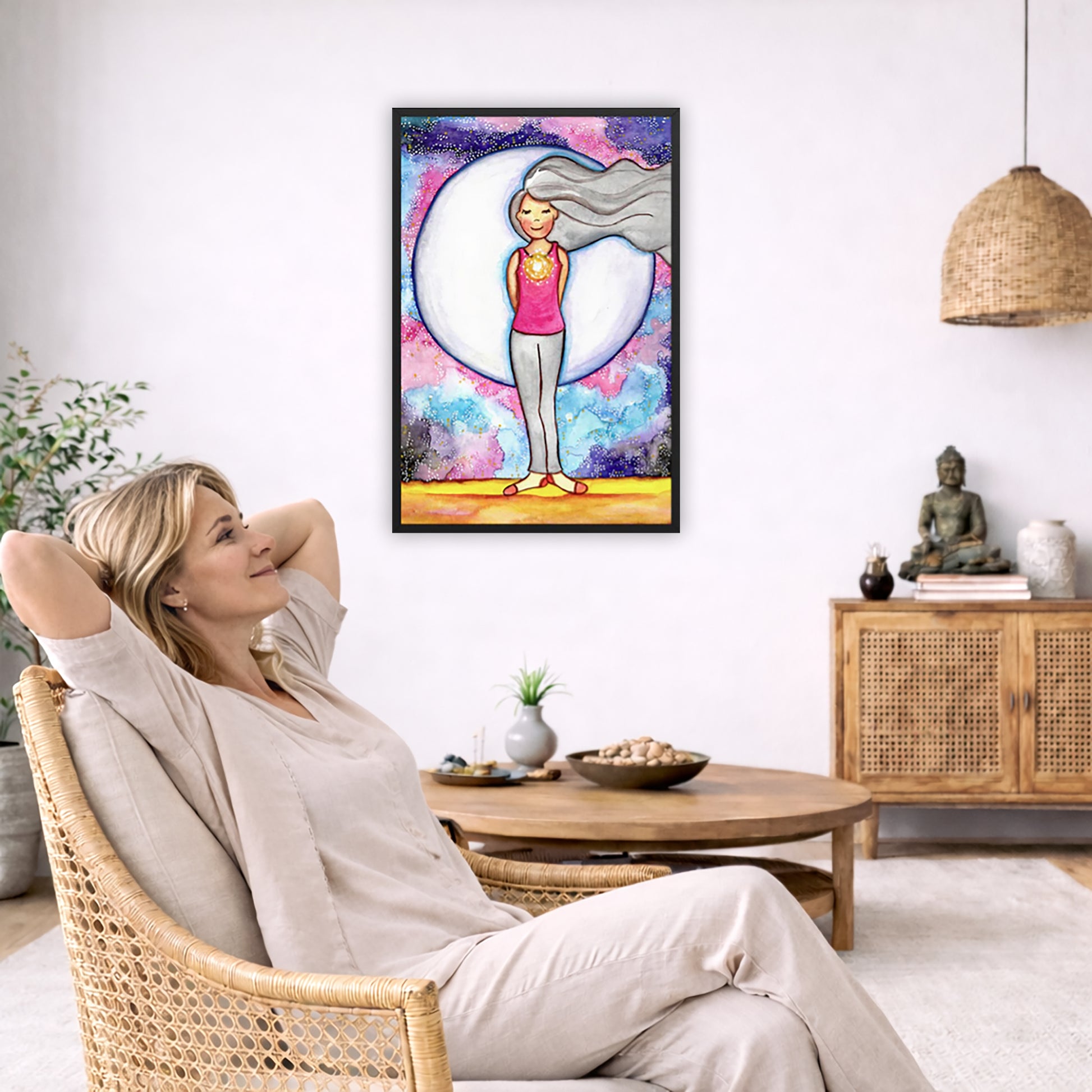 Framed poster of a woman's heart chakra glowing with beautiful love energy. The poster is in the center of the living room wall. To the left a woman is relaxing in her chair with her hands behind her head. There is a small coffee table beside her with a bowl of walnuts, incense and a small green plant. On the right side of the room is a cabinet with a Buddha statue, books and an urn on it. To the left is a green floor plant.
