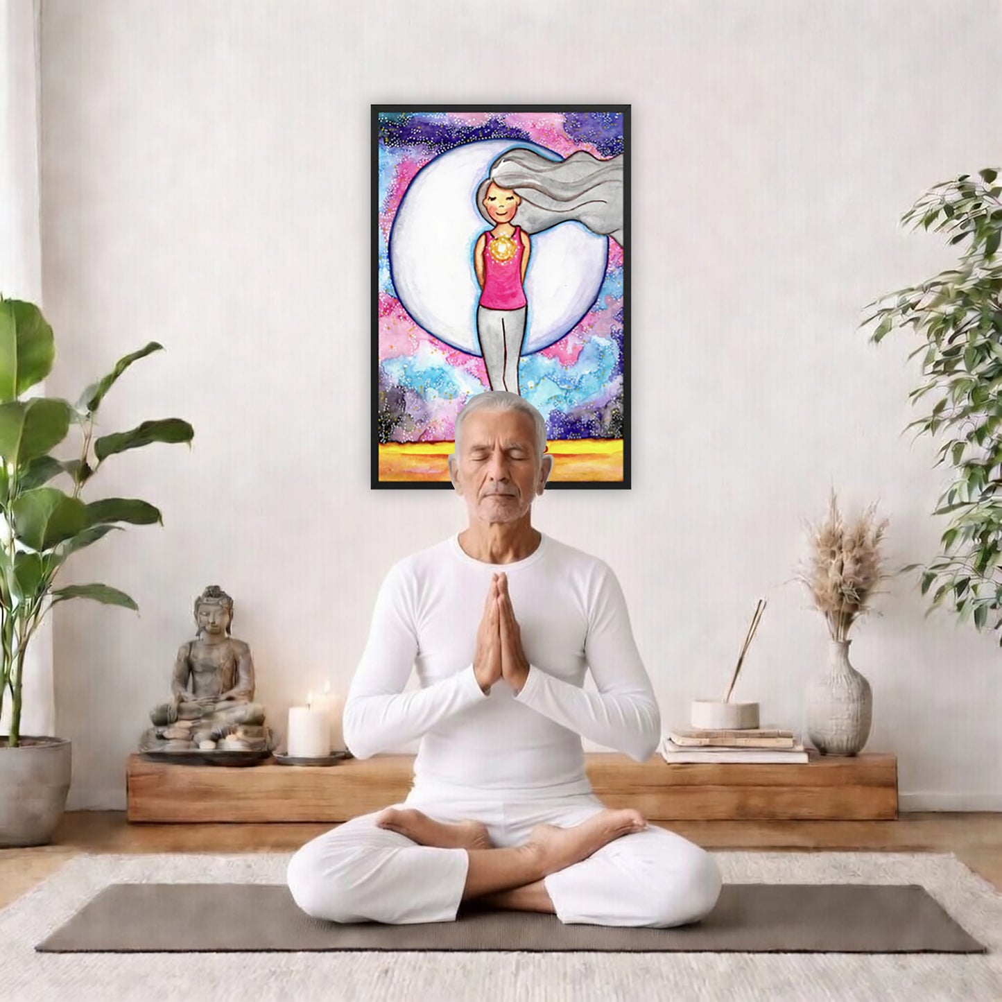 Framed poster of a woman's heart chakra glowing with beautiful love energy.   The poster is framed hanging on a living room wall. A man is mediating facing the poster. There is a coffee table in front of him with burning candles and a Buddha statue. There are green potted plants on each side of the room.
