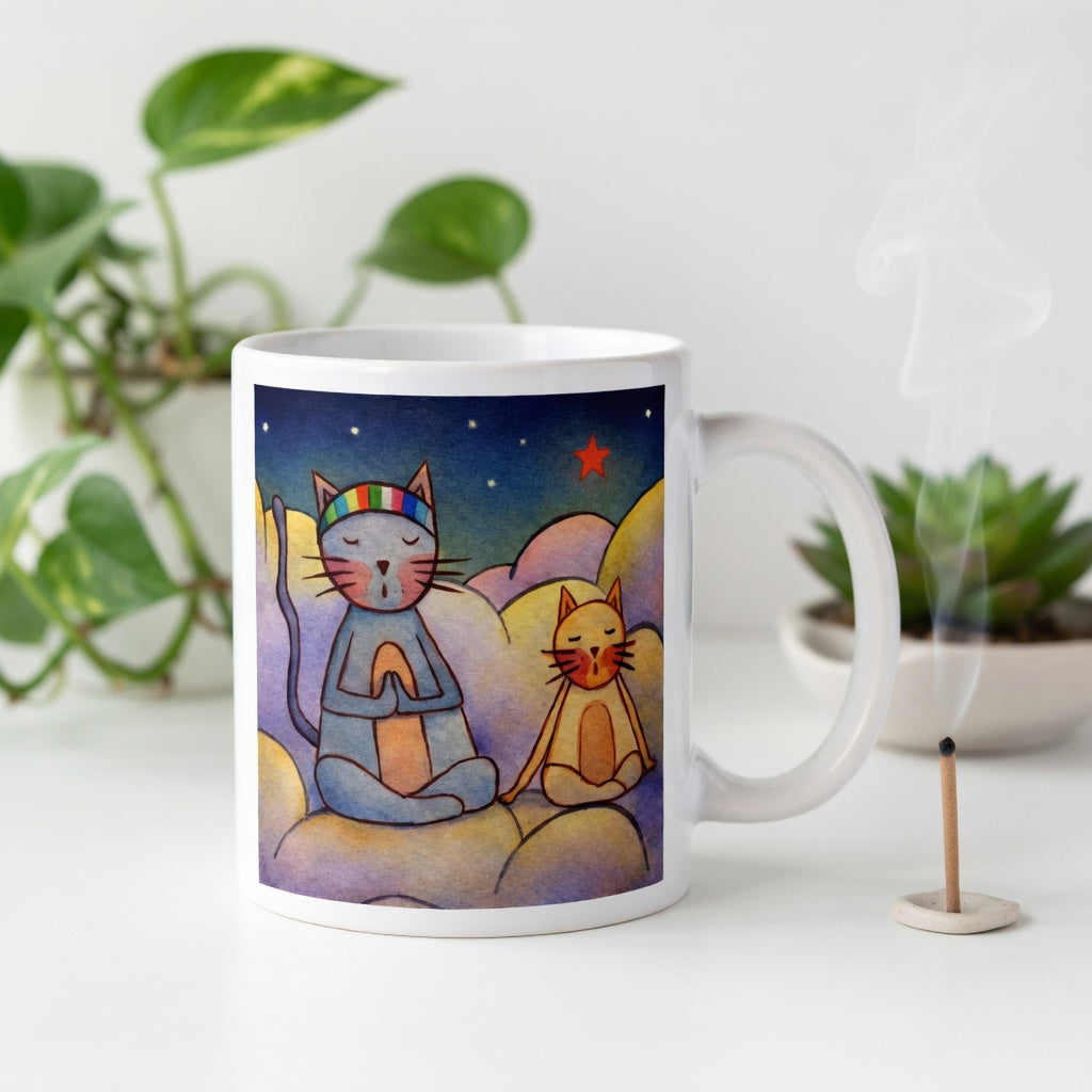 Two cats meditating on a cloud under the night sky mindfulness mug. Incense is burning beside the mug. There are green potted plants in the background.
