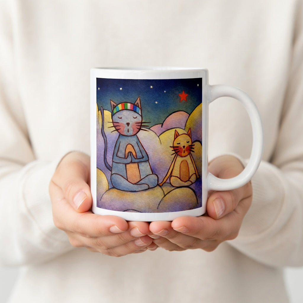 Two cats meditating on a cloud under the night sky mindfulness mug.  The hands of a person wearing a white shirt are holding the mug up to display the design.