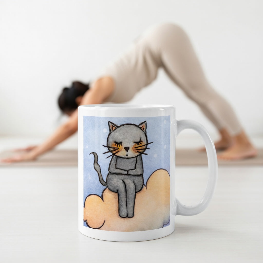 Gray cat Meditating on an orange cloud mindfulness coffee mug.  The mug is in front of a woman doing the yoga posture downward facing dog.