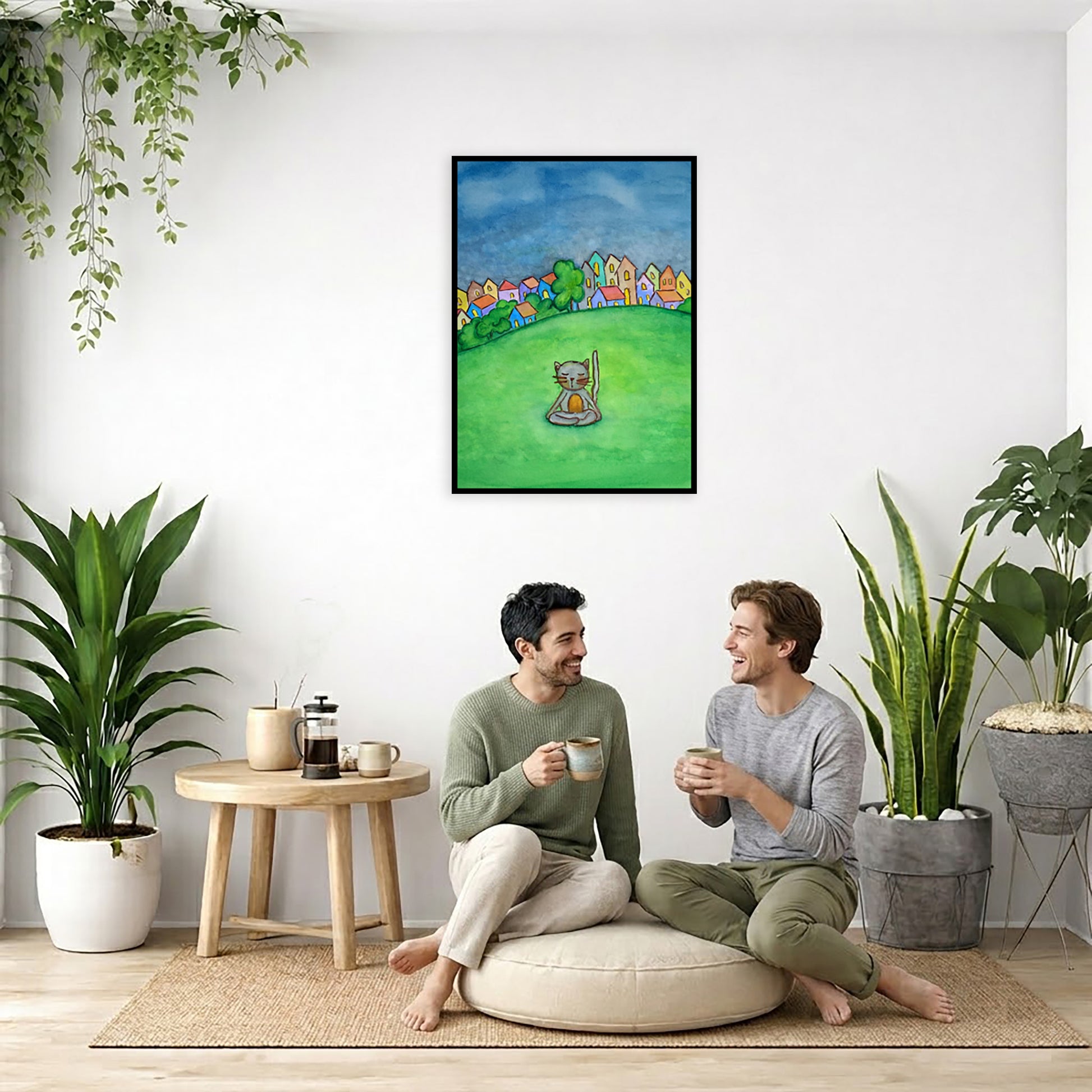 A gray cat meditating in the park framed poster. This is a print of the original hand-painted watercolor by Brazilian artist Thaís Suizo.  The poster is in the center of the living room wall. Two men are sitting on a giant pillow having a coffee. Beside them is a small tray with a pot of coffee and incense. To the left is a green floor plant and a hanging green plant. To the right of them is a green floor plant.