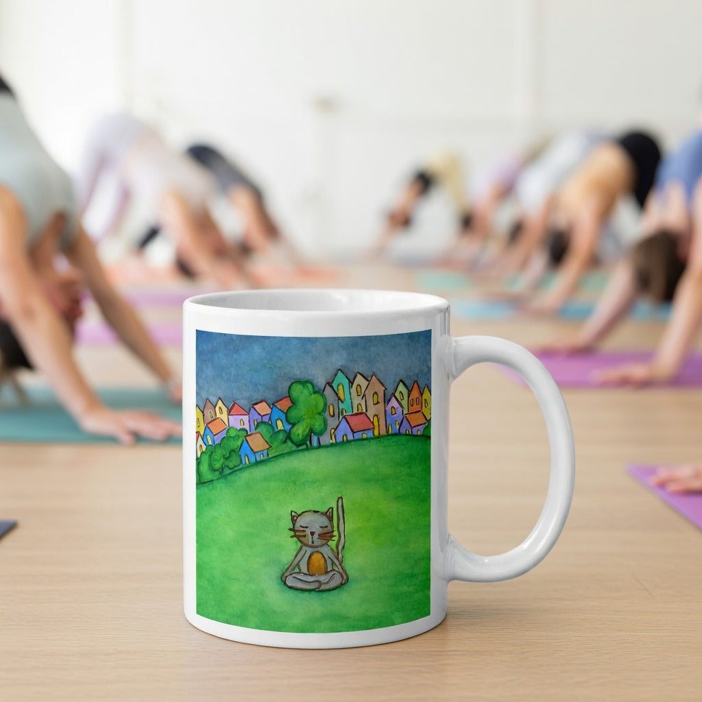 Gray cat meditating peacefully in a park surrounded by a large lawn and a row of houses in the distant background coffee mug. The mug is in front of a yoga class doing the downward facing dog posture.