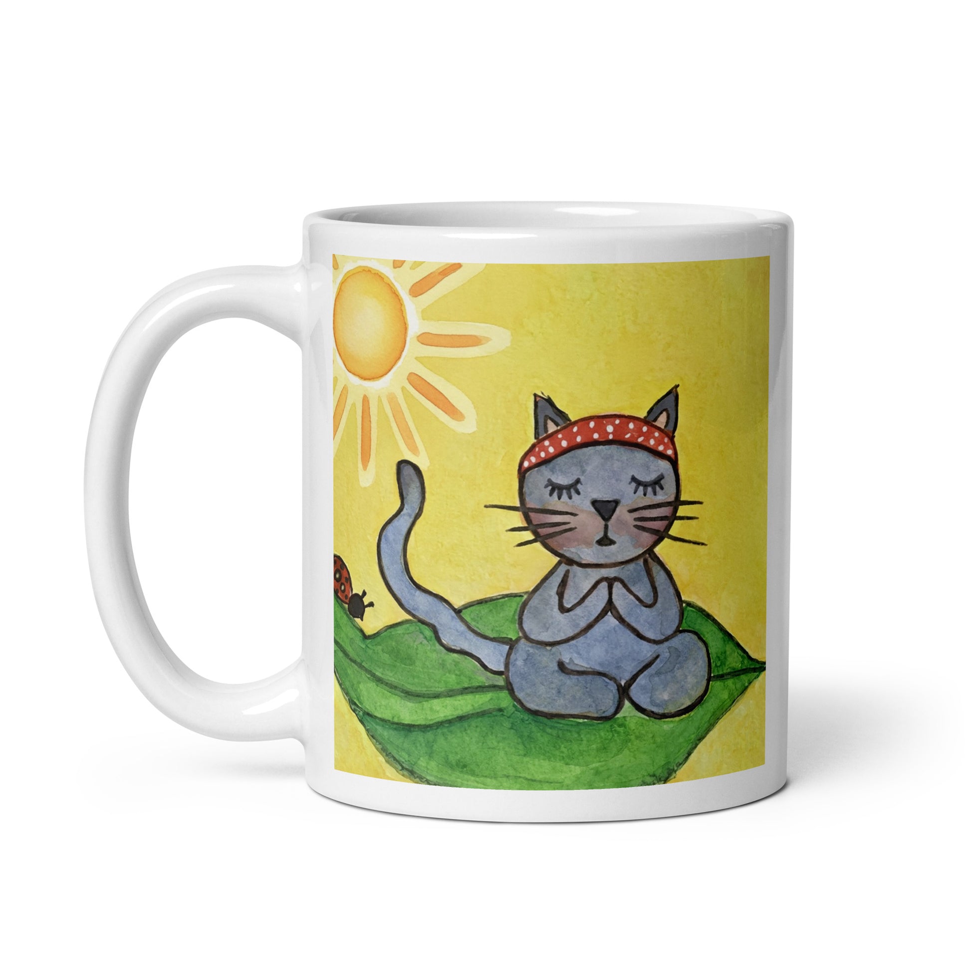 Gray cat meditating peacefully on a leaf in the bright sunlight meditation mug. This illustration of a cat meditating is on both sides of the mug. In this image the handle of the mug is on the left side.