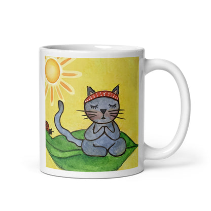 Gray cat meditating peacefully on a leaf in the bright sunlight meditation mug. This illustration of a cat meditating is on both sides of the mug. In this image the handle of the mug is on the right side.