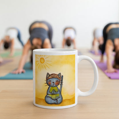 Gray cat meditating on a sunny day mindfulness mug.  Incense is burning beside the mug.  The mug is in front of a yoga class doing the downward facing dog posture.