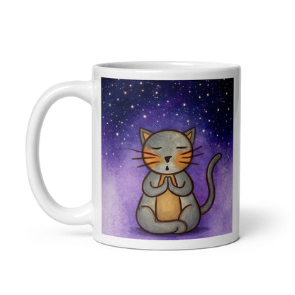 Gray cat meditating under a starry night sky with a peaceful mindfulness coffee mug. This illustration of a cat meditating is on both sides of the mug. In this image the handle of the mug is on the left side.