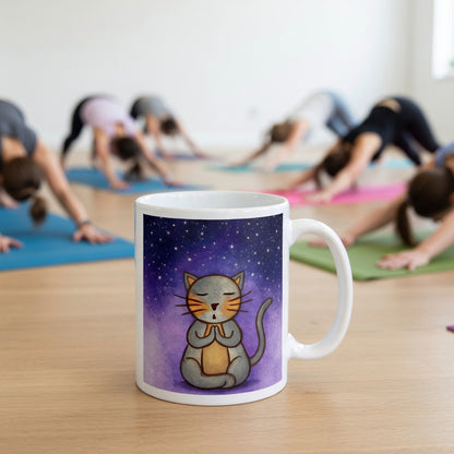 Gray cat meditating under a starry night sky with a peaceful mindfulness coffee mug.  The mug is in front of a yoga class doing the downward facing dog posture.