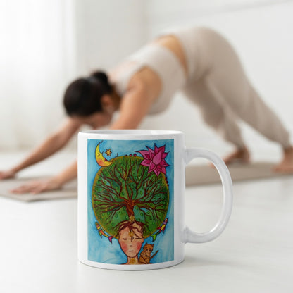 Poster of the crown chakra of a woman opening up like the tree of life.   The mug is in front of a woman doing the yoga posture downward facing dog.