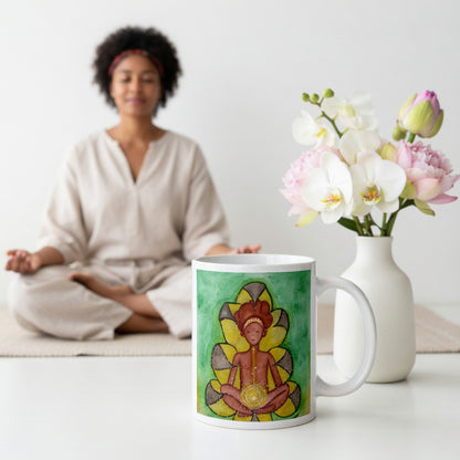Meditating figure with glowing sacral chakra below the navel, representing creativity, passion and emotional flow, spiritual chakra artwork on a coffee mug. The mug is sitting  with flowers beside it. A woman is meditating in the background.