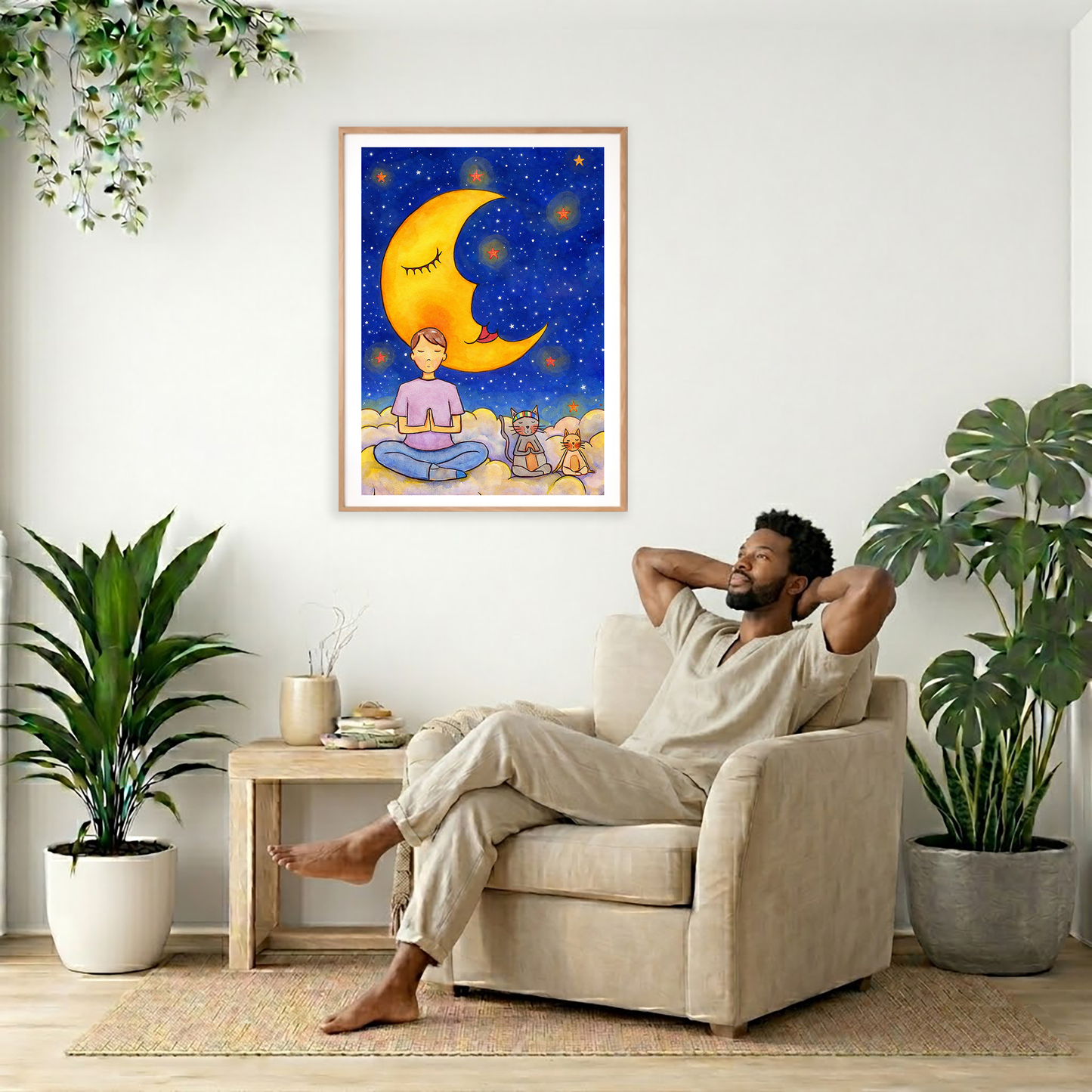 Man with cats meditating under the moonlight on mindfulness poster.   The poster is framed and is in the center of the living room wall. To the right a woman is relaxing in a chair with his hands behind his head. To the left is a green floor plant and a hanging green plant. To the right of them is a green floor plant.
