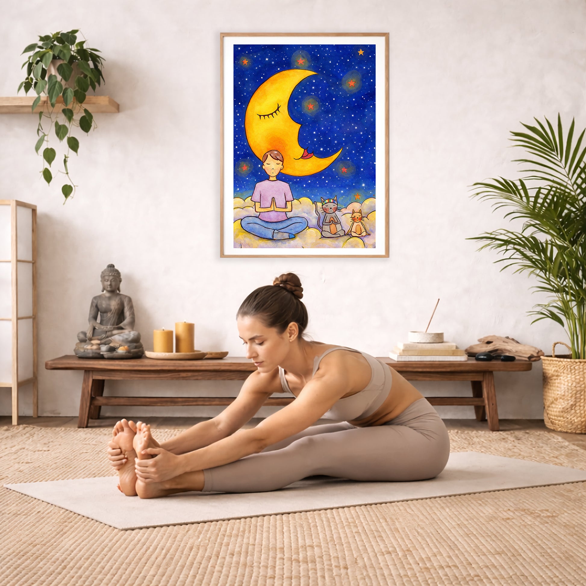 Man with cats meditating under the moonlight on mindfulness poster.  The poster is framed and is in the center of the living room wall. A woman is doing a sitting forward bend on her yoga mat. There is a coffee table below the poster with burning candles, incense, a Buddha statue and a big piece of driftwood.
