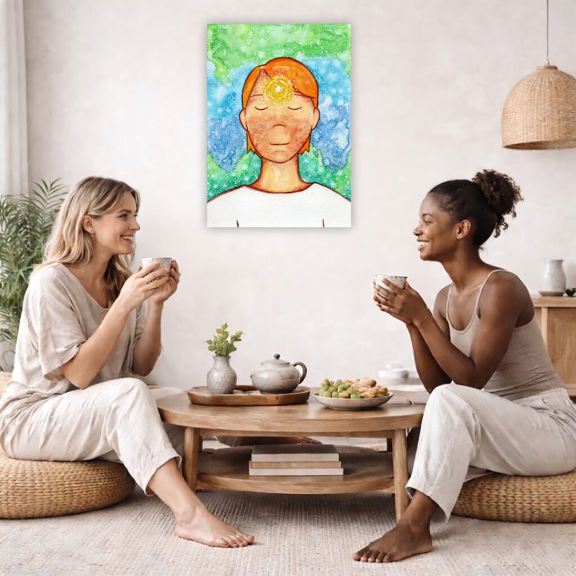 Man meditating with his brow chakra glowing canvas print. The poster is in the center of the living room wall. Two female friends are having tea, grapes and cookies on a coffee table in front of the poster. On the left there is a green potted plant and to the right there is a hanging lamp.
