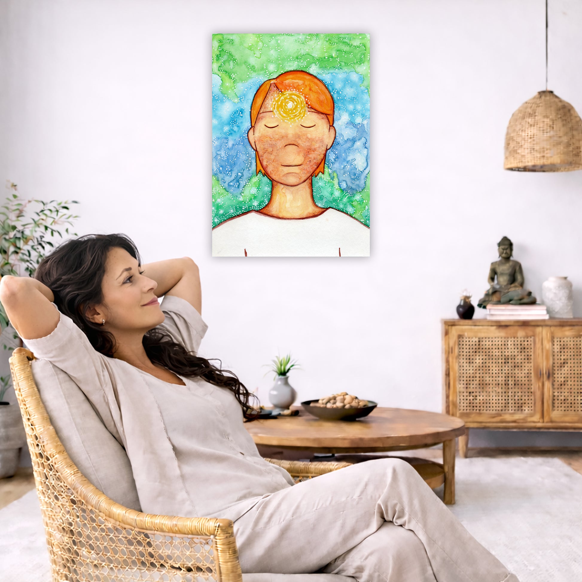 Man meditating with his brow chakra glowing canvas print.  The poster is in the center of the living room wall. To the left a woman is relaxing in her chair with her hands behind her head. There is a small coffee table beside her with a bowl of walnuts, incense and a small green plant. On the right side of the room is a cabinet with a Buddha statue, books and an urn on it. To the left is a green floor plant.